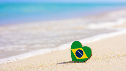 Flag of Brazil in the shape of a heart on a sandy beach. The concept of the best vacation in Brazil...