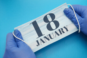 18 january day of month. Doctor holding an antivirus mask in blue medical gloves on blue...