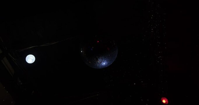 The Disco Ball reflects multi-colored rays. Night club interior. Dark party background with copy space