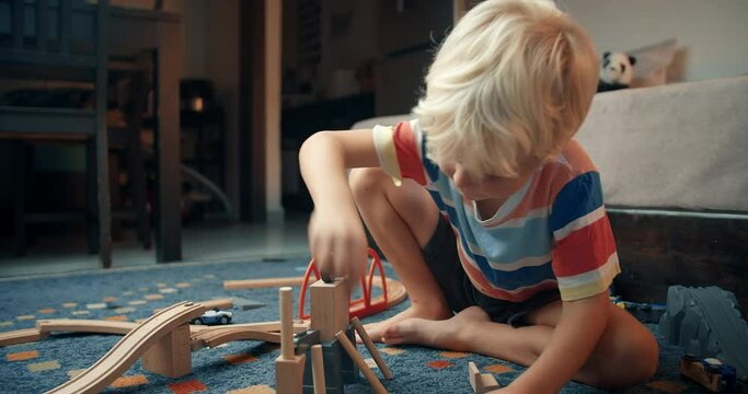 Happy cute children playing in living room with wooden blocks building something using part of railway road toy. Concept of carefree childhood baby boy enjoying and learning construction. 