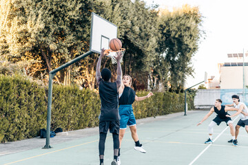 Four friends playing basketball in a public outdoor court