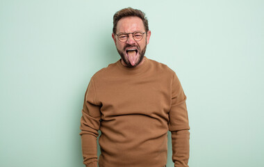 middle age handsome man feeling disgusted and irritated, sticking tongue out, disliking something...