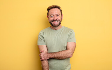 middle age handsome man laughing shyly and cheerfully, with a friendly and positive but insecure...