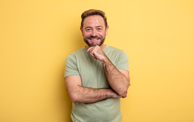 middle age handsome man looking happy and smiling with hand on chin, wondering or asking a...