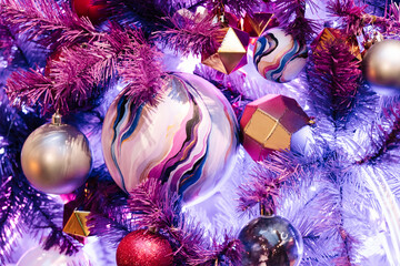 Christmas balls and glowing garlands on a purple christmas tree