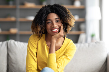 Fototapeta na wymiar Portrait Of Attractive Black Woman Sitting On Couch And Smiling At Camera