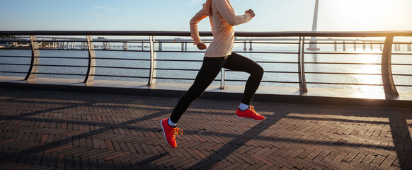 Fitness woman runner running on seaside bridge