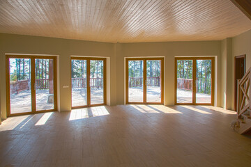 Fototapeta premium A spacious hall in a wooden house with large windows in the woods
