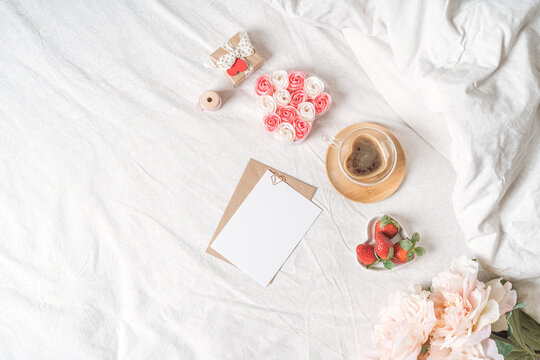 Spring, summer still life composition for valentine day. Blank greeting card mockup scene with heart shaped cup of coffee, strawberries, and roses flowers. Breakfast in bed. Flat lay, top view