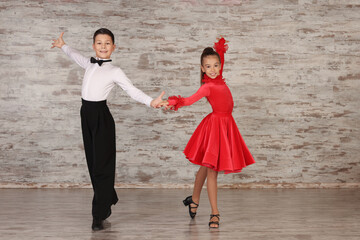 Beautifully dressed couple of kids dancing together in studio