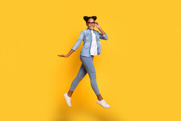 Fototapeta na wymiar Full size profile side photo of young african girl jump up walk eyewear wear casual clothes isolated over yellow color background