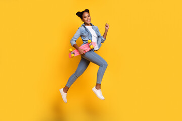Fototapeta na wymiar Full body profile side photo of young african lady good mood go walk run hold skateboard isolated over yellow color background