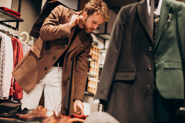 Young handsome man choosing cloth at shop