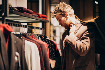 Young handsome man choosing cloth at shop