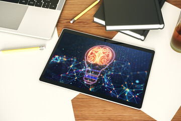 Modern digital tablet monitor with creative light bulb hologram with human brain, idea and brainstorming concept. Top view. 3D Rendering