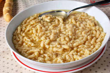 Homemade Passatelli in chicken broth. Selective focus.