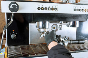 The girl unscrews the holder from the coffee machine to pour out the used coffee.