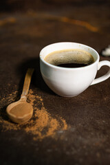cup of coffee on table with wooden spoon with cinnamon 