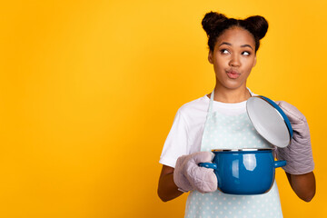 Photo of young african girl housewife wondered dreamy look empty space cooker isolated over yellow color background