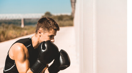 Man exercising and fighting in outside, boxer in gloves. male boxer portrait