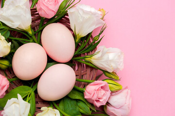 Obraz na płótnie Canvas Easter background with Easter eggs and spring flowers. Top view with copy space. Nest with eggs decorated with beautiful flowers on a pink background.