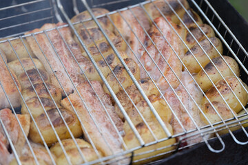 Fresh raw chicken legs and potatoes on grill gridiron in nature