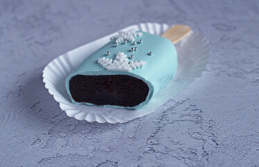New Year's festive cake in glaze on a stick in section on a blue background