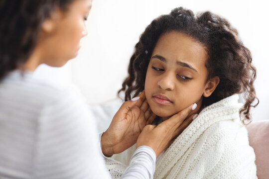 African american mother rubbing her sick daughter neck