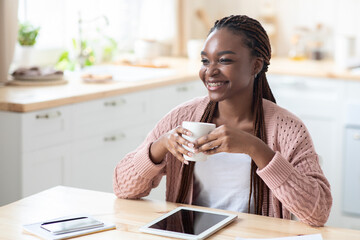 Positive African American Woman Drinking Coffee And Using Digital Tablet In Kitchen