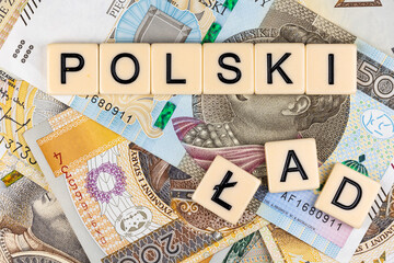 The sentence "Polski Ład" translated as  "Polish Order" and many Polish banknotes. New taxation rules in Poland. Photo taken under artificial, soft light