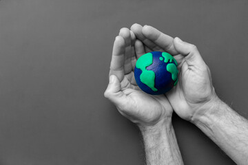 Black and white man's hands holding the Earth in color