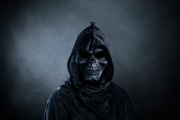 Grim reaper over dark misty background
