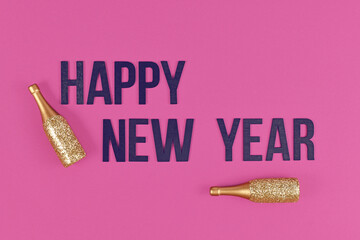 Happy new year text with by golden champagne bottles on pink background