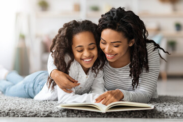 Pretty black girl reading book with her mom