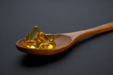 vitamins in a wooden spoon, tablets and pills in a spoon. medicines are on the table. pills on a...