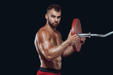 Side view of a male athlete putting a disc on a barbell isolated on black background