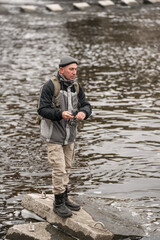 Man fishing on the river. Fisherman with a fishing rod on the background of water in cloudy weather