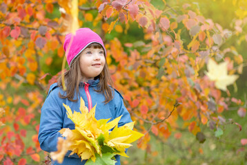 Portrait of a young girl with Downs syndrome holding bouquet of autumn leaves. Empty space for text