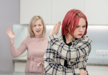 Family conflict. Angry mother screams at afraid teen daughter, girl ignoring her mom and shows stop gesture. Family relationships