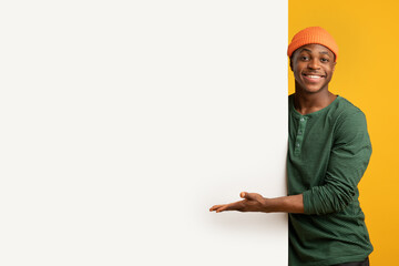 Nice Offer. Cheerful Black Guy Pointing At White Advertisement Board With Palm