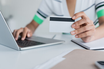 cropped view of african american woman holding credit card and using laptop
