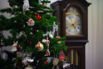 Decorated Christmas tree closeup. Decoration element on the faux Christmas tree in the house against the background of an old clock. New Year background concept.