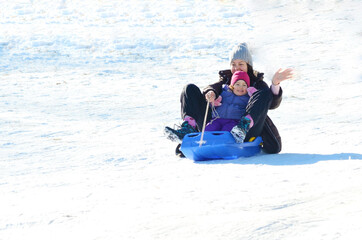 Fototapeta na wymiar Little Kid in Sled with her Mother .Winter Fun 
