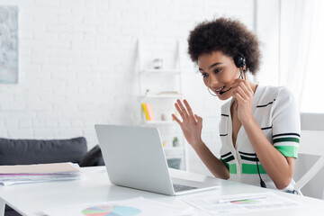 African american freelancer in headset having video call on laptop at home