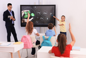 Teacher and pupil using interactive board in classroom during lesson