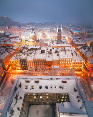 Gorgeus cityscape of winter Lviv city glowing by city lights with roofs covered by snow from top of...