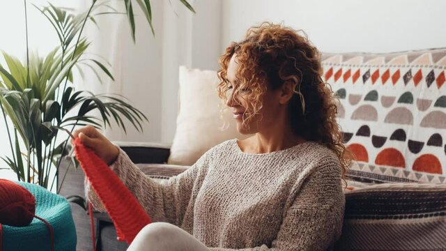 Adult woman enjoy at home knitting work leisure activity sitting on the carpet in living room. Female people have fun and relax with woolen knit activity leisure indoor