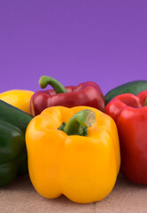 Colourful bell peppers, vegetables on grunge cement against blue gradient background.