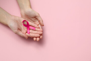 Woman holding pink ribbon on color background, top view with space for text. Breast cancer...