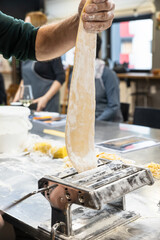The process of making homemade pasta using a pasta machine. The image can be an illustration of the process of making pasta at home or in a culinary master class.